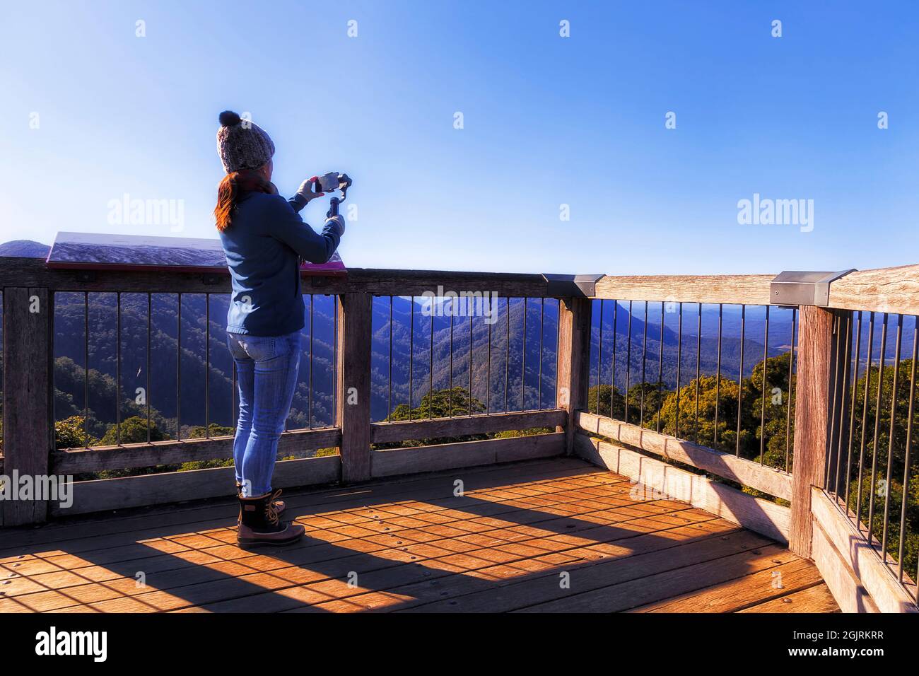Junge Frau auf der abgelegenen Aussichtsplattform des Skywalk im Dorrigo National Park von australien, die die Szenarienansicht auf dem Smartphone filmte und Selfies aufnahm. Stockfoto