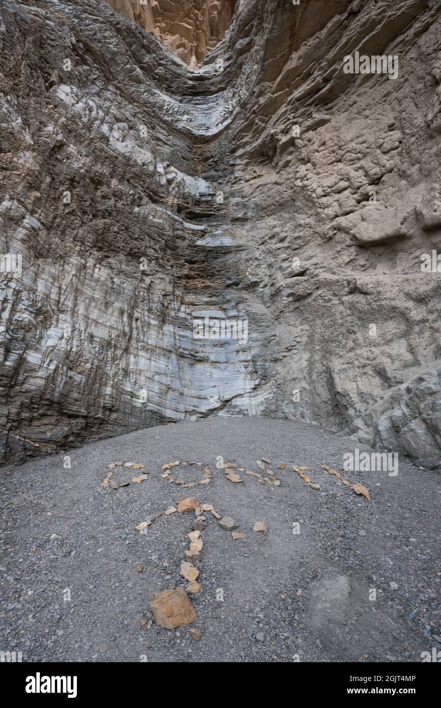 Das Felsschild sagt den Leuten, dass sie den Dry Waterfall am Ende des Mosaic Canyon im Death Valley National Park nicht besteigen sollen Stockfoto