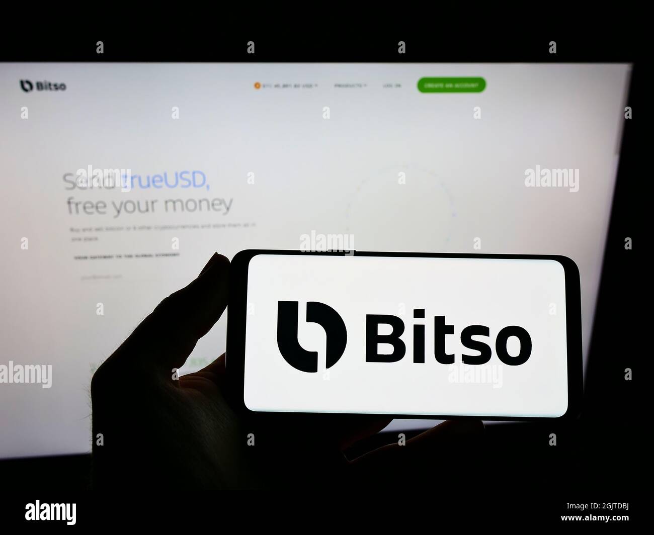 Person, die ein Mobiltelefon mit dem Logo der mexikanischen Kryptowährungsbörse Bitso auf dem Bildschirm vor der Business-Webseite hält. Konzentrieren Sie sich auf die Telefonanzeige. Stockfoto