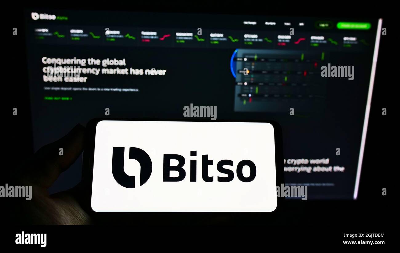 Person, die Mobiltelefon mit dem Logo der mexikanischen Kryptowährungsbörse Bitso auf dem Bildschirm vor der Business-Webseite hält. Konzentrieren Sie sich auf die Telefonanzeige. Stockfoto