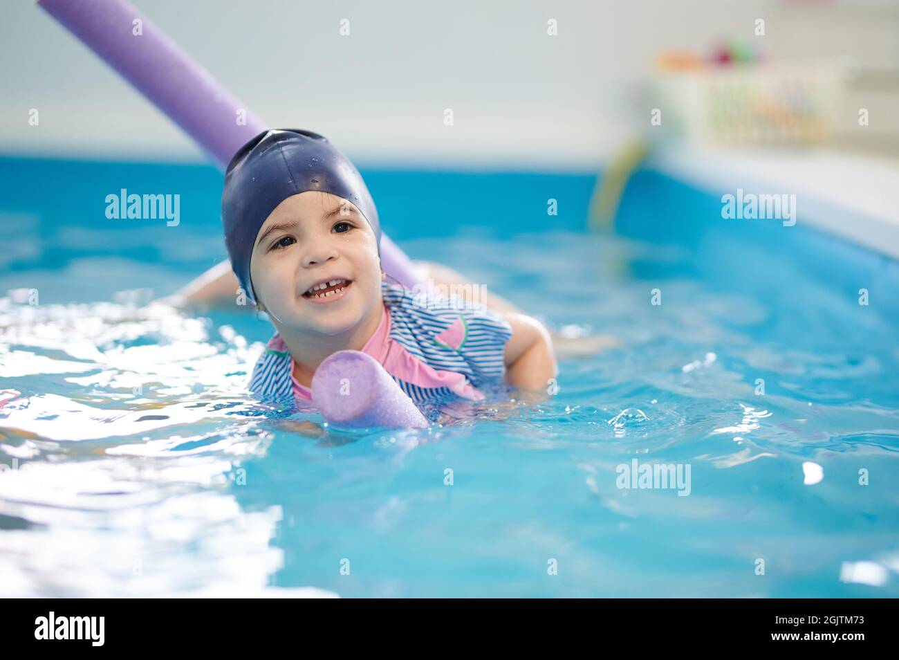 Kind schwimmt auf einem schwimmenden Rohr. Kinder nehmen an Schwimmunterricht Stockfoto
