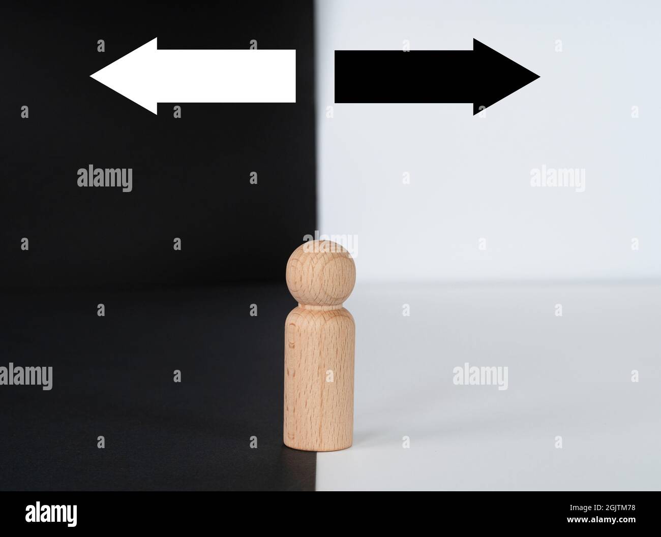 Geschäftskonzept. Entscheidungsfindung dargestellt von einer Holzfigur mit zwei Pfeilen auf schwarzem und weißem Hintergrund. Selektive Fokuspunkte. Stockfoto