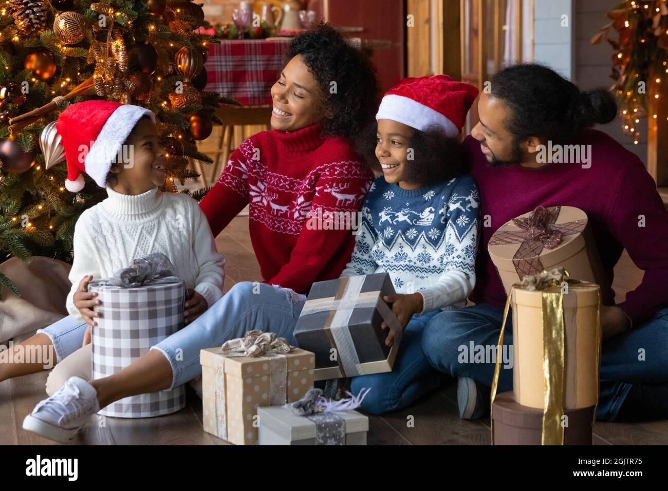 Glückliche Biracial Familie mit Kindern packen Weihnachtsgeschenke aus Stockfoto