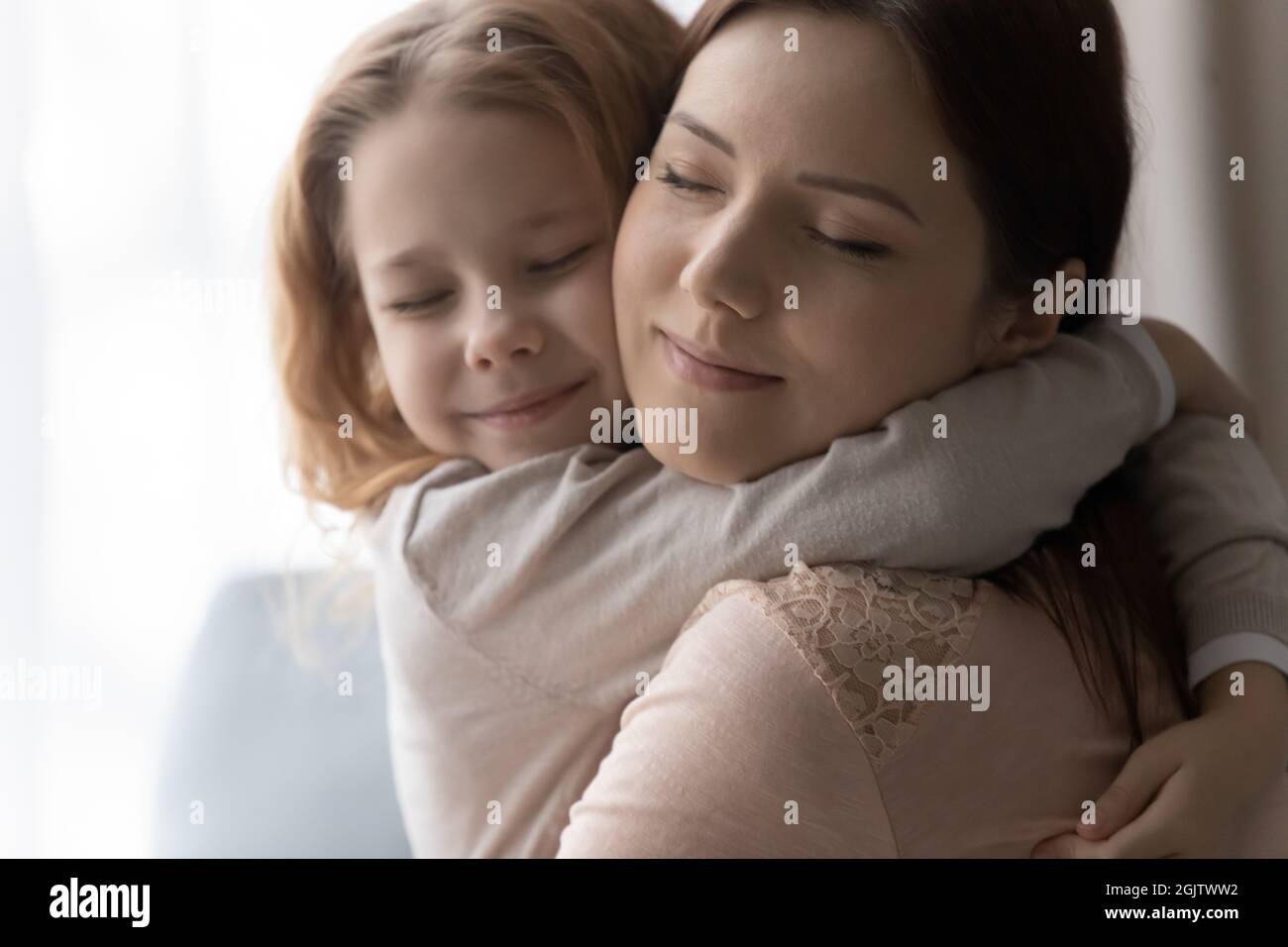 Aufrichtige liebevolle kleine Mädchen kuscheln junge Mutter. Stockfoto