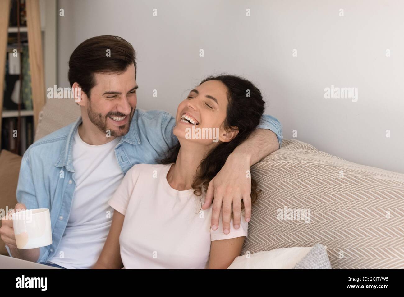 Fröhliches Paar verliebt Kaffee trinken lachend entspannend auf dem Sofa Stockfoto