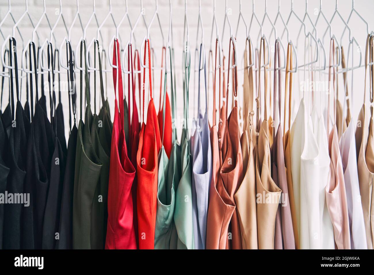 Bunte Kleider hängen an Kleiderbügeln im Laden. Verkauf von Frauenkleider Stockfoto