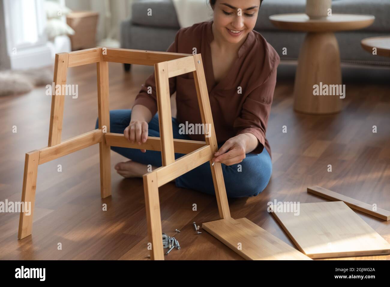 Fokussierte indische Frau verwenden einfache Werkzeuge sammeln Selbstmontage Möbel Stockfoto