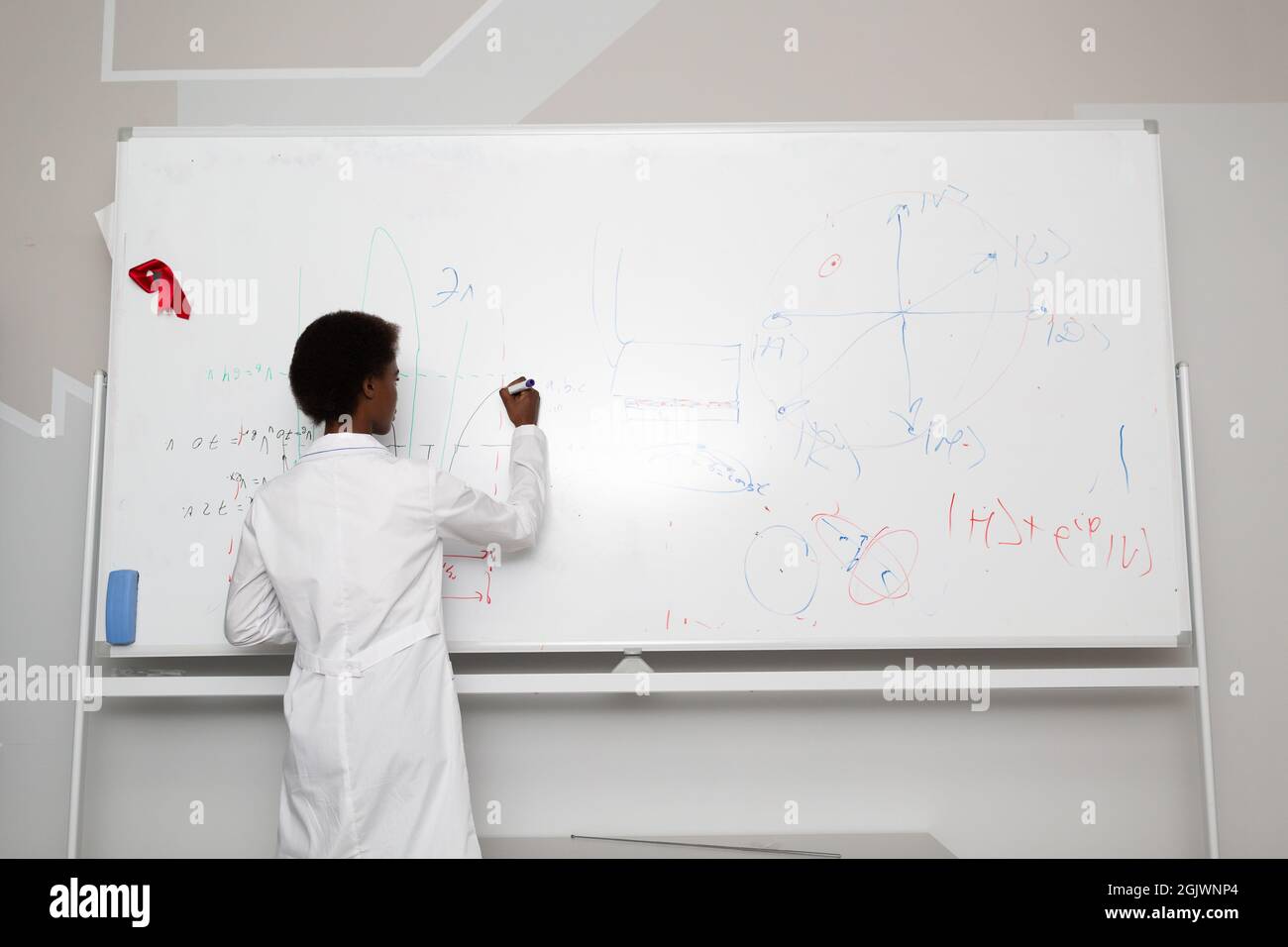 Afroamerikanische Mathematiklehrerin schreibt auf Tafel mit Marker. Stockfoto