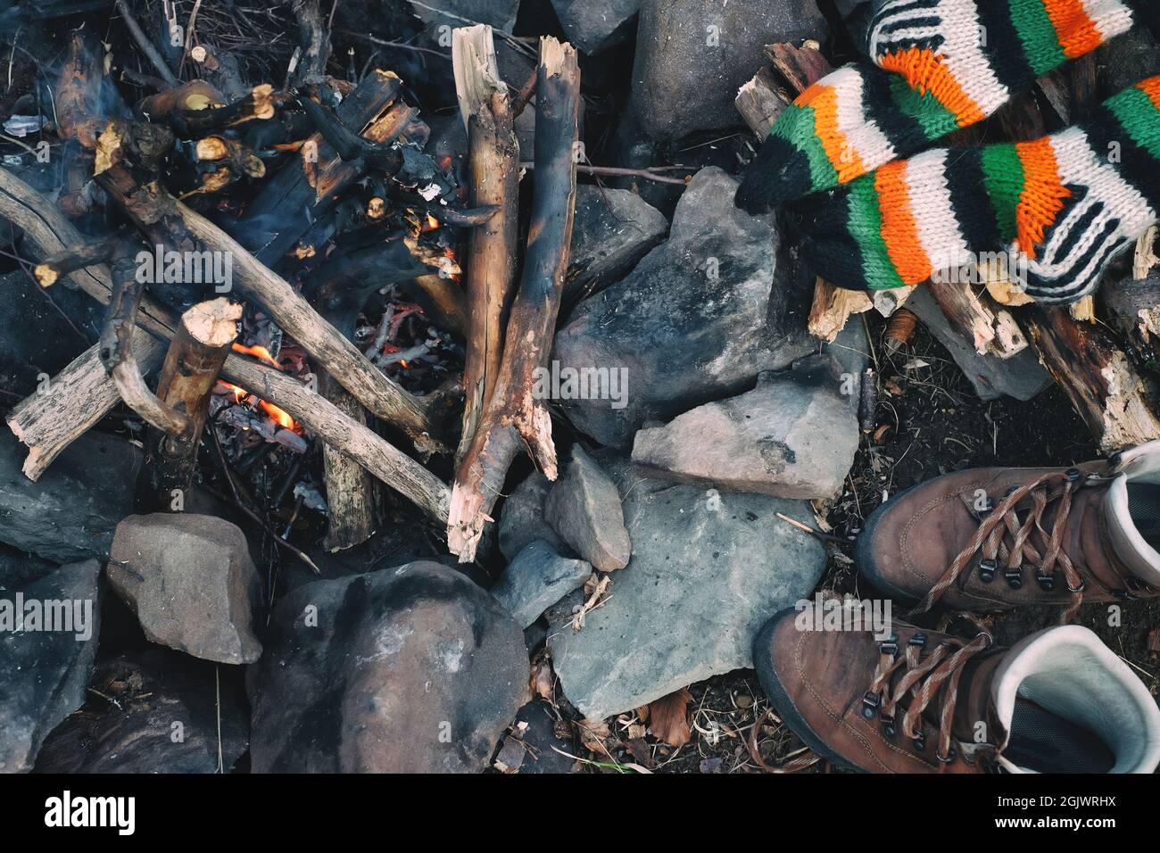 Camping Rest Konzept. Gestrickte Socken, Wanderschuhe trocknen in der Nähe eines Lagerfeuers im Wald Stockfoto
