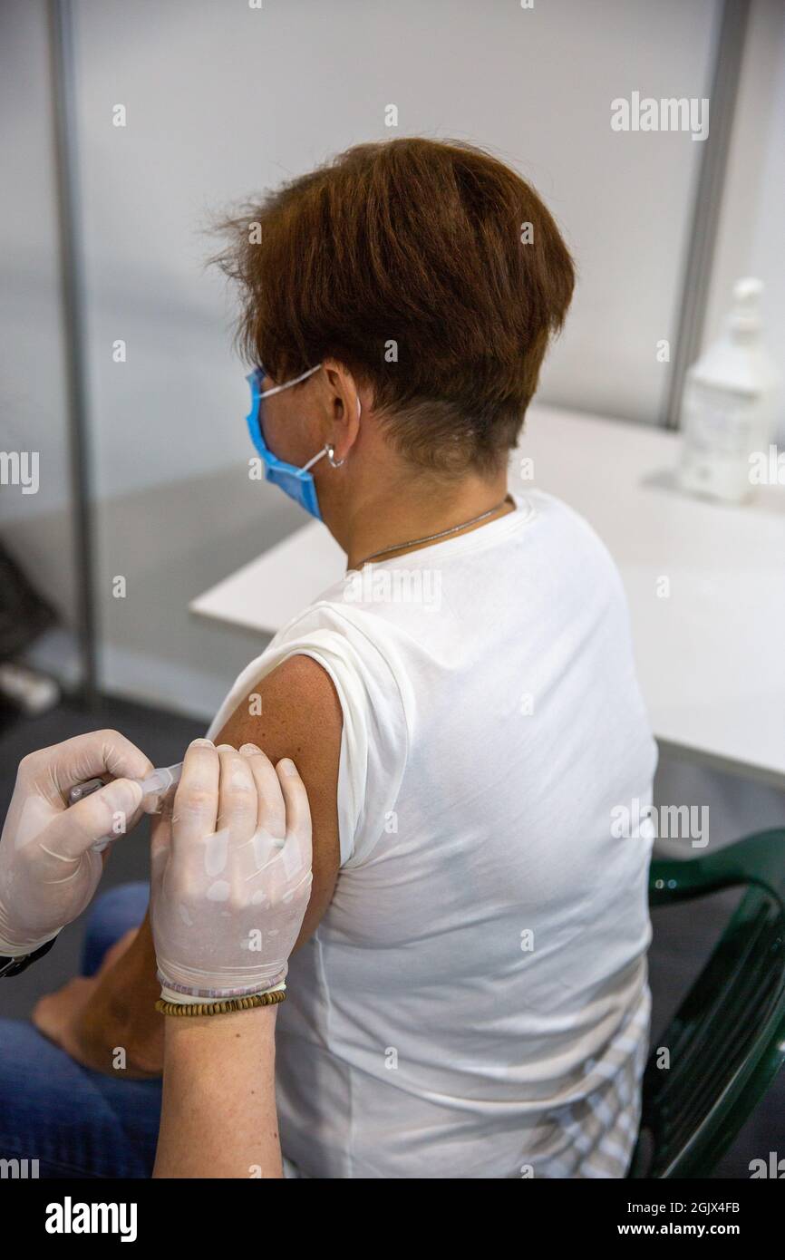 Frau mittleren Alters, von einer Krankenschwester gegen das Coronavirus im COVID-19-Massenimpfzentrum geimpft. Stockfoto