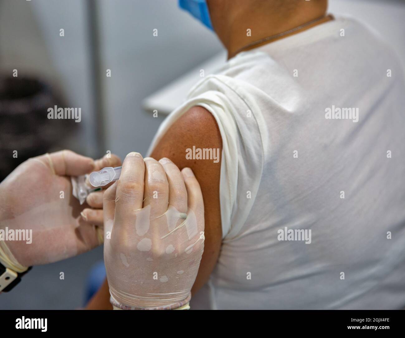 Frau mittleren Alters, von einer Krankenschwester gegen das Coronavirus im COVID-19-Massenimpfzentrum geimpft. Stockfoto