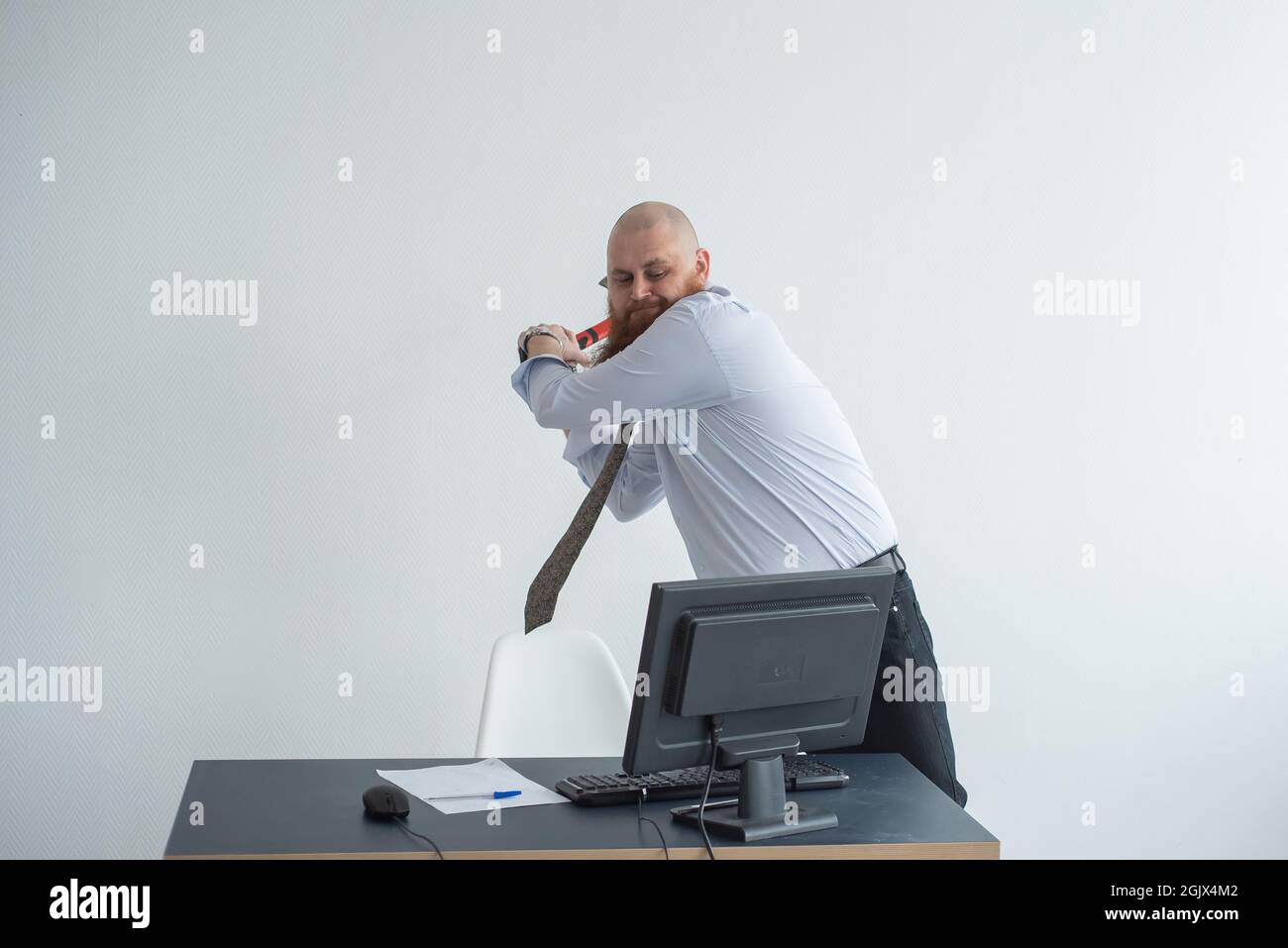 Gestresste verrückte Geschäftsmann zerschlagen seinen Computer im Büro mit Axt Problem Konzept. Der Mann hat Probleme bei der Arbeit und Frustration. Stockfoto