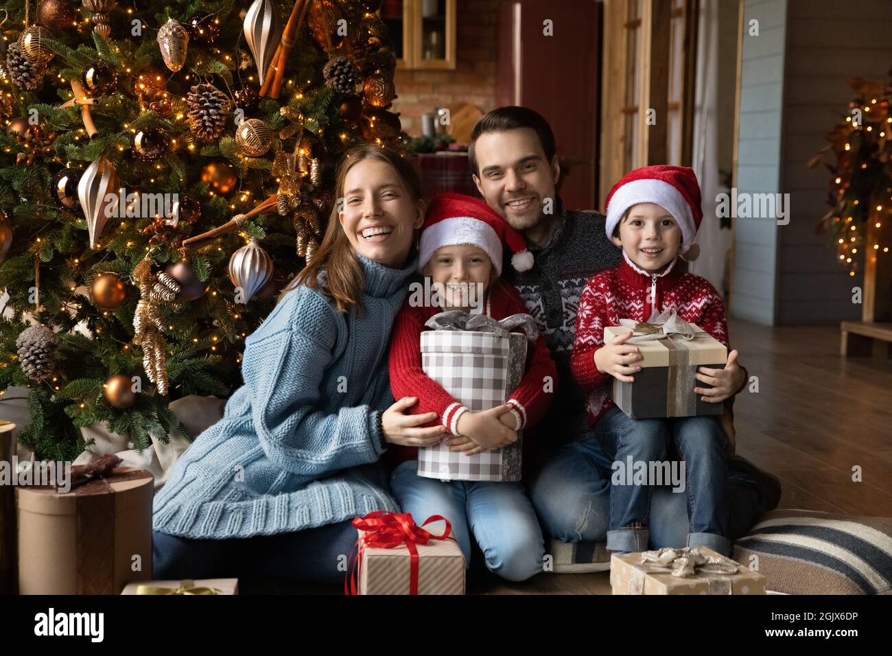 Porträt einer emotionalen glücklichen Familie, die in der Nähe eines geschmückten Weihnachtsbaums sitzt. Stockfoto