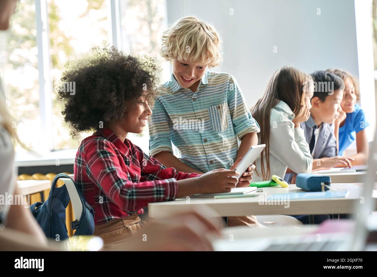 Afroamerikanisches Mädchen und kaukasischer Junge Schulkinder arbeiten im Klassenzimmer zusammen. Stockfoto
