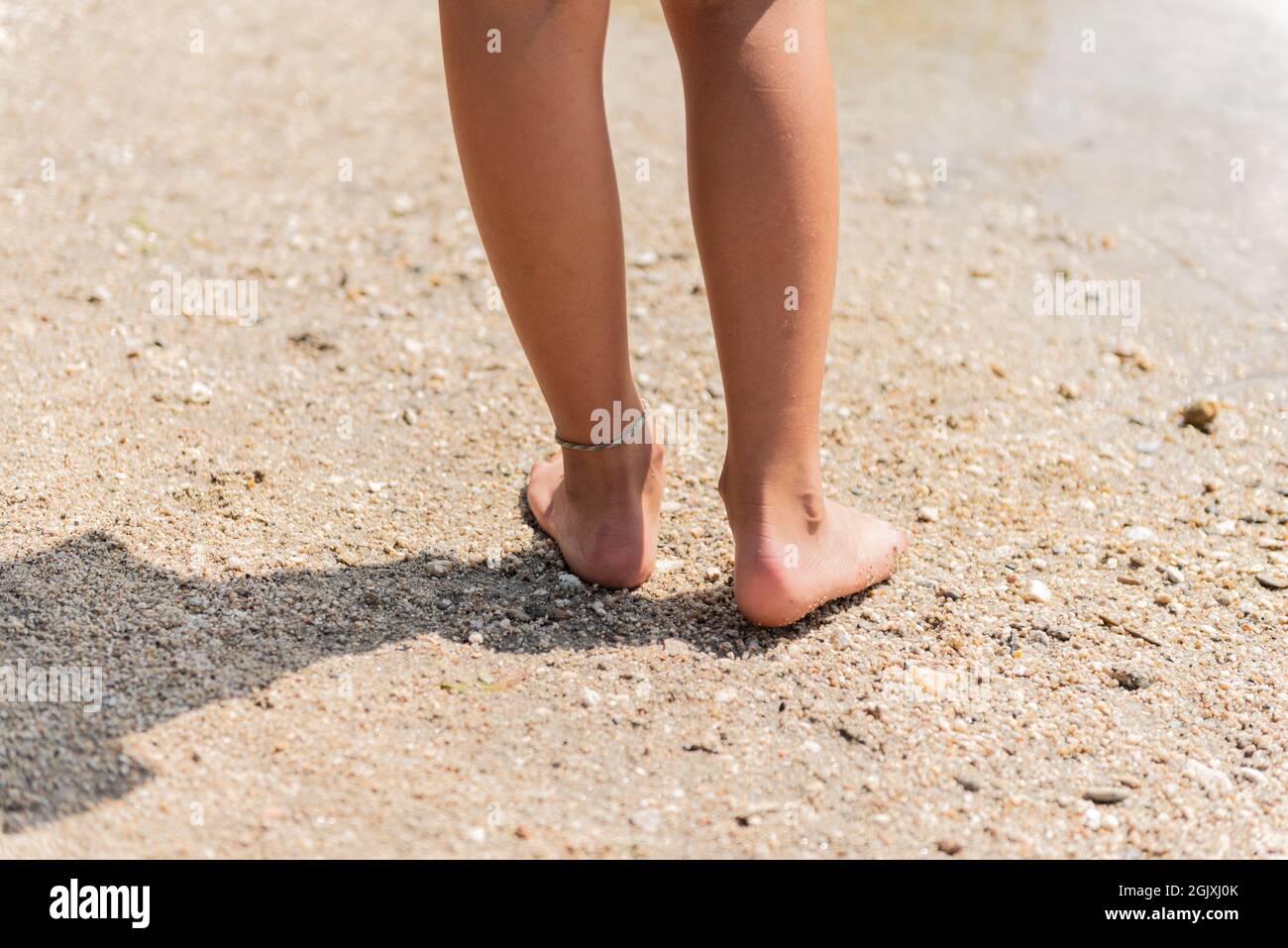Rückansicht der Füße und Beine beim Spazierengehen am Flussstrand. Stockfoto
