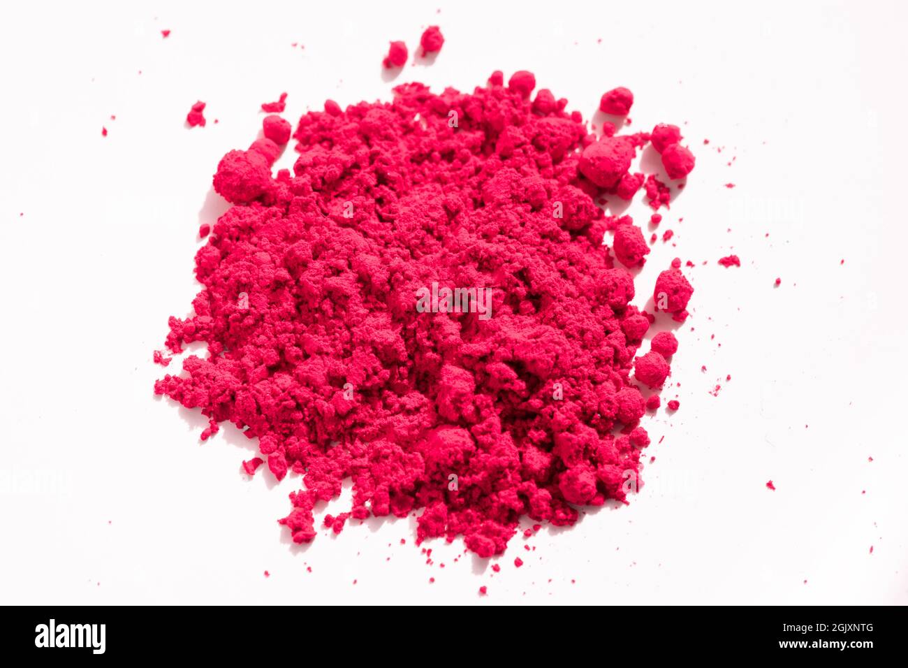 Nahaufnahme eines Teils des roten Pigments, das auf Weiß isoliert ist. Das Pigment kann als Basis für Make-up verwendet oder mit Leinöl gemischt werden, um Ölfarbe zu machen Stockfoto