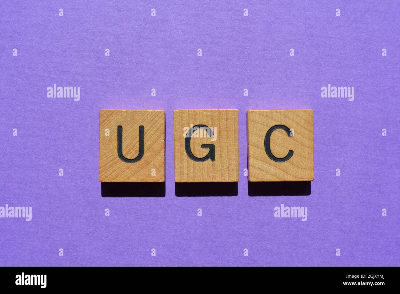 UGC, Akronym für User Generated Content in Holzbuchstaben, isoliert auf violettem Hintergrund Stockfoto