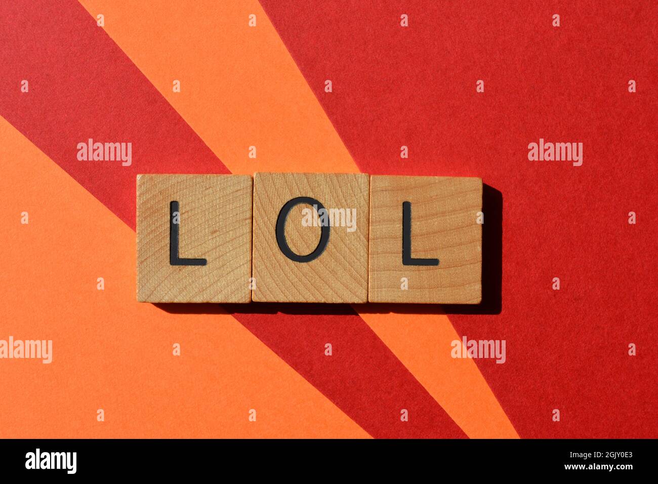 LOL Akronym für Laughing Out Loud in hölzernen Buchstaben, isoliert auf farbigem rotem und orangefarbenem Hintergrund Stockfoto