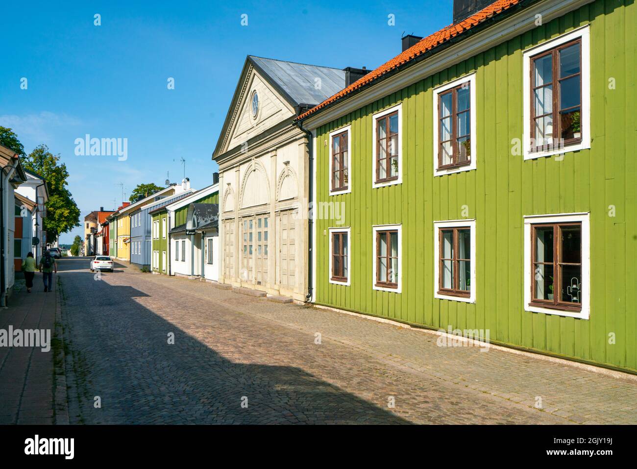 Vastervik, Schweden - 08.23.2021: Straße in der Nähe des Zentrums mit alten, traditionellen bunten Holzhäusern im skandinavischen Stil. Sonniger Sommertag. Stockfoto