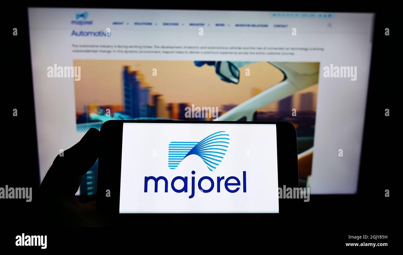 Person, die das Smartphone mit dem Logo des Dienstleistungsunternehmens Majorel Group Luxembourg S.A. auf dem Bildschirm vor der Website hält. Konzentrieren Sie sich auf die Telefonanzeige. Stockfoto