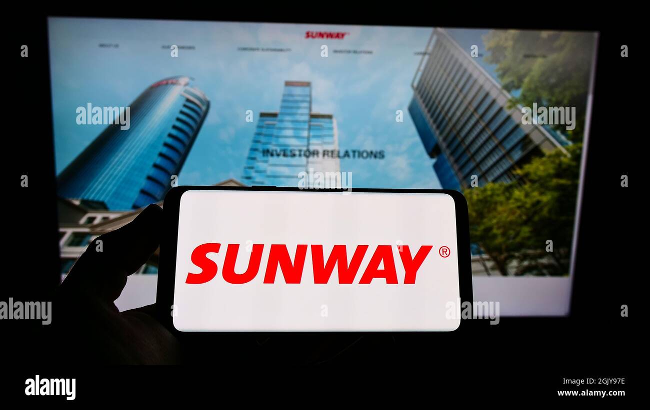 Person, die das Smartphone mit dem Logo des malaysischen Konglomerats Sunway Berhad auf dem Bildschirm vor der Website hält. Konzentrieren Sie sich auf die Telefonanzeige. Stockfoto