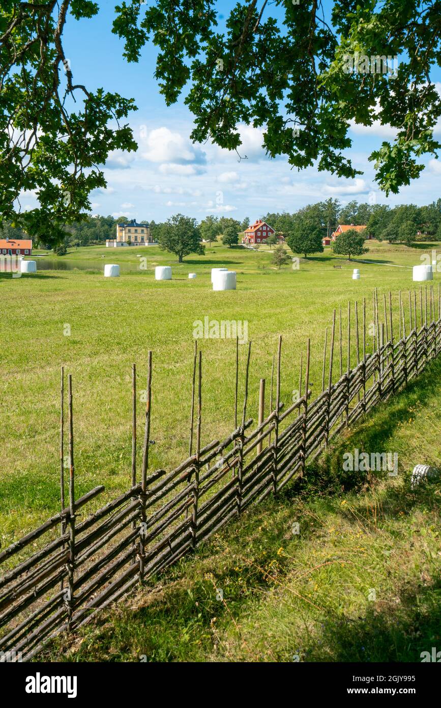 Vertikale Aufnahme einer kleinen Siedlungsfarm in Südschweden an einem schönen sonnigen Sommertag. Urlaub in der schwedischen Landschaft. Vintage Zaun und weiß Stockfoto