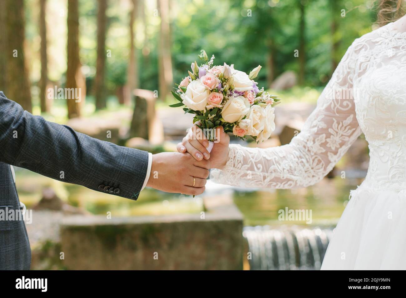 Der Bräutigam reicht der Braut einen Hochzeitsstrauß. Nahaufnahme von frisch vermählten Händen und zartem Bouquet Stockfoto