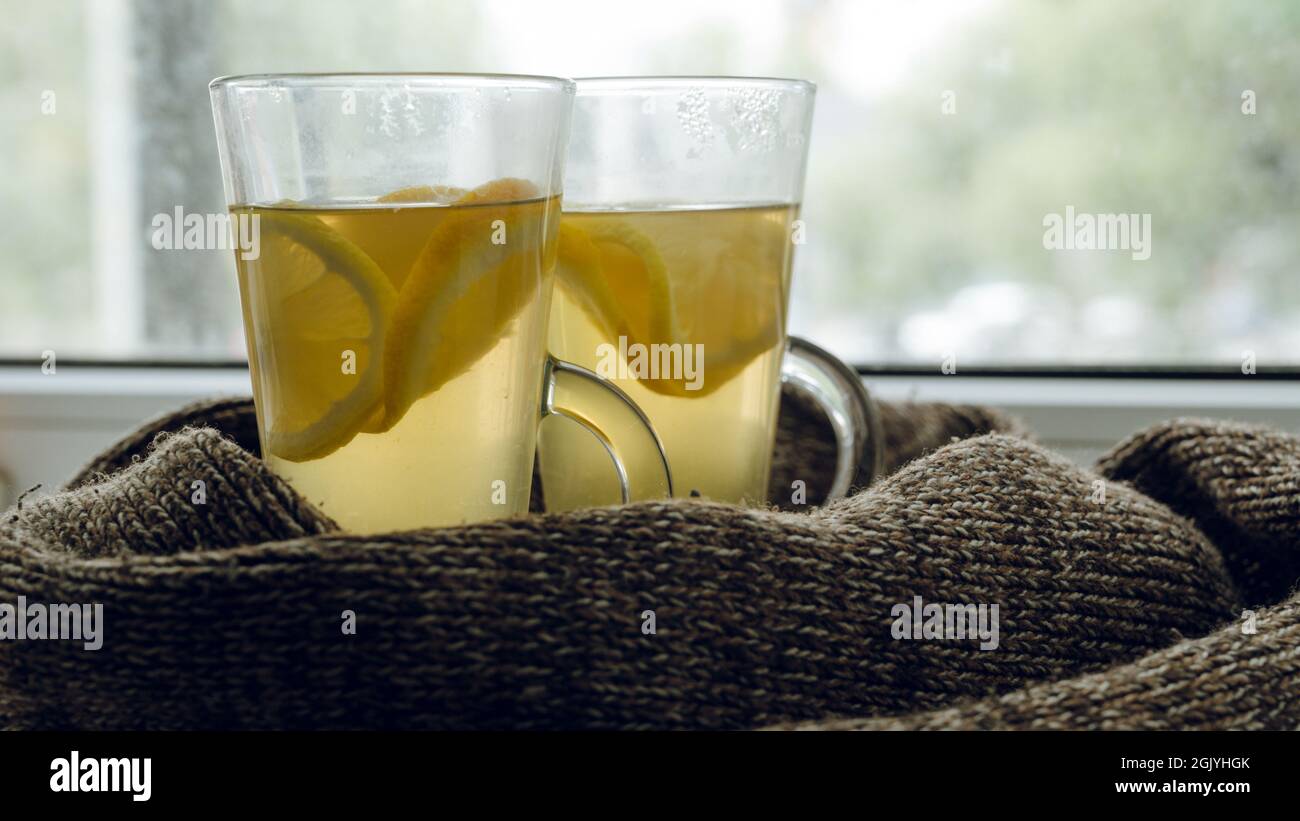 Nahaufnahme von einigen Gläsern mit Vitamin-Grüntee mit Zitrone und Orange. Strickschal. Gesundes heißes Getränk bei kaltem Wetter. Stockfoto