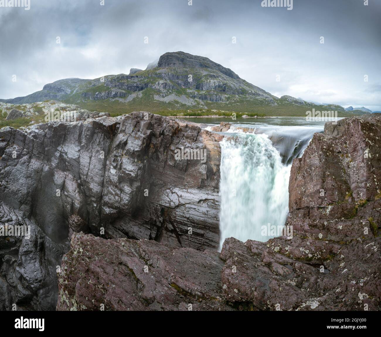 Nahaufnahme des mächtigen Stuor Muorkkegarttje Wasserfalls am Fluss Lulealven an einem teils bewölkten Tag im arktischen Sommer. Stora Sjofallet Stockfoto