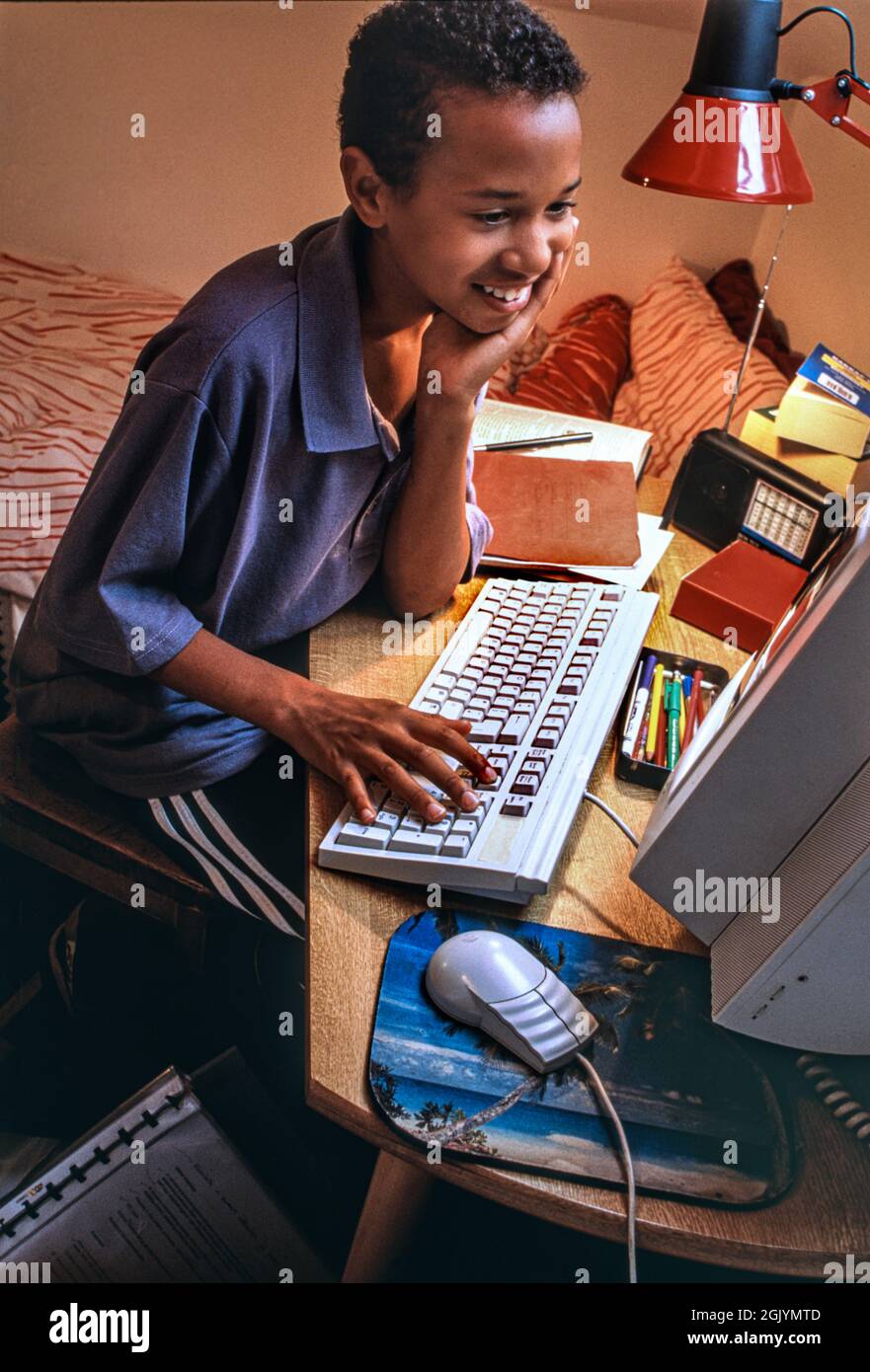 First Computer Fashion Style 1990s Surfen Schlafzimmer Boy 7-9 Jahre Afrikanische Karibik in seinem Schlafzimmer glücklich entspannt Surfen spielen Studium auf seinem ersten Computer 1995 Ära Stockfoto