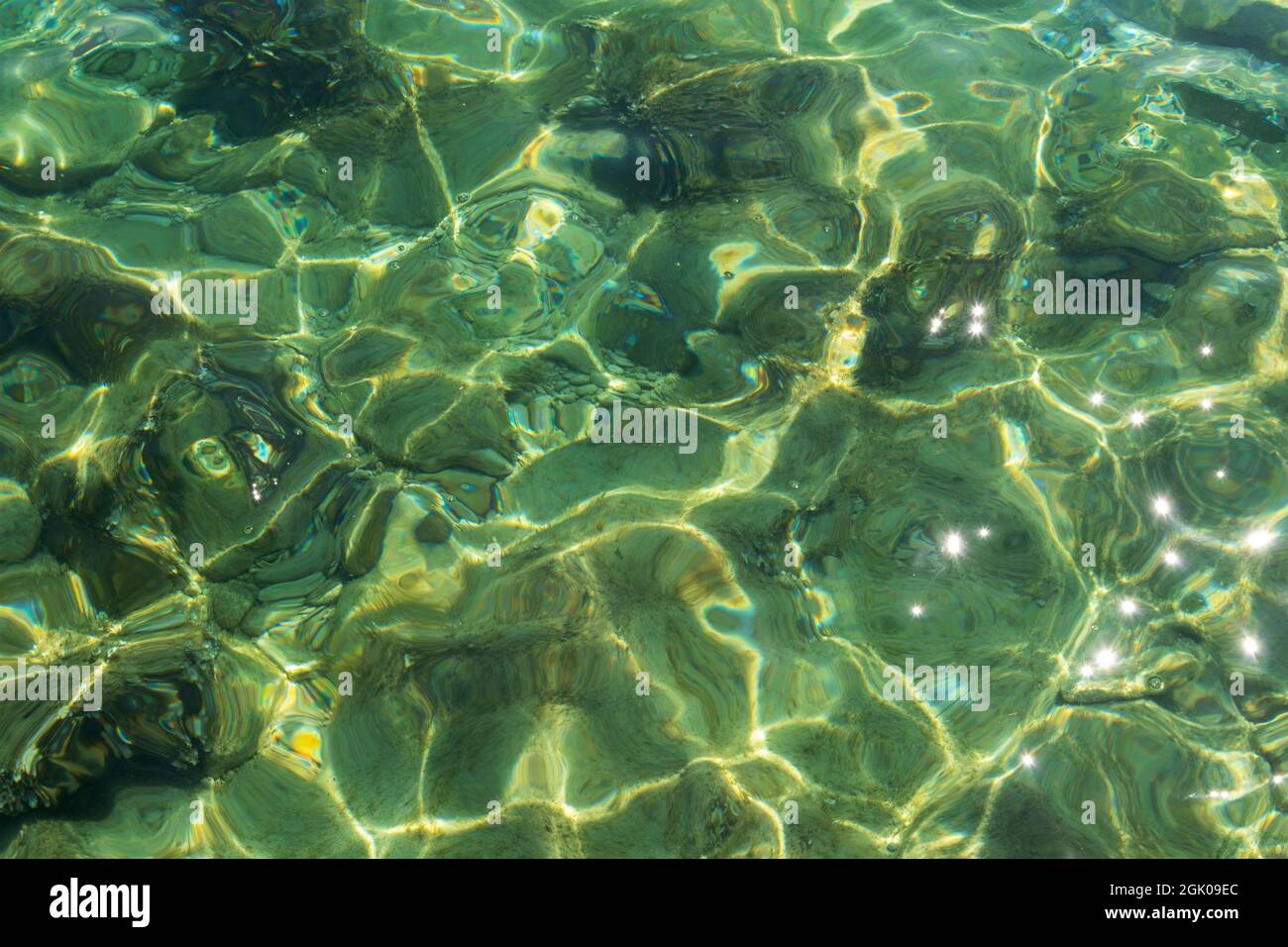 Transparente Meeresoberfläche mit Sonneneinstrahlung, Textur, Hintergrund. Stockfoto