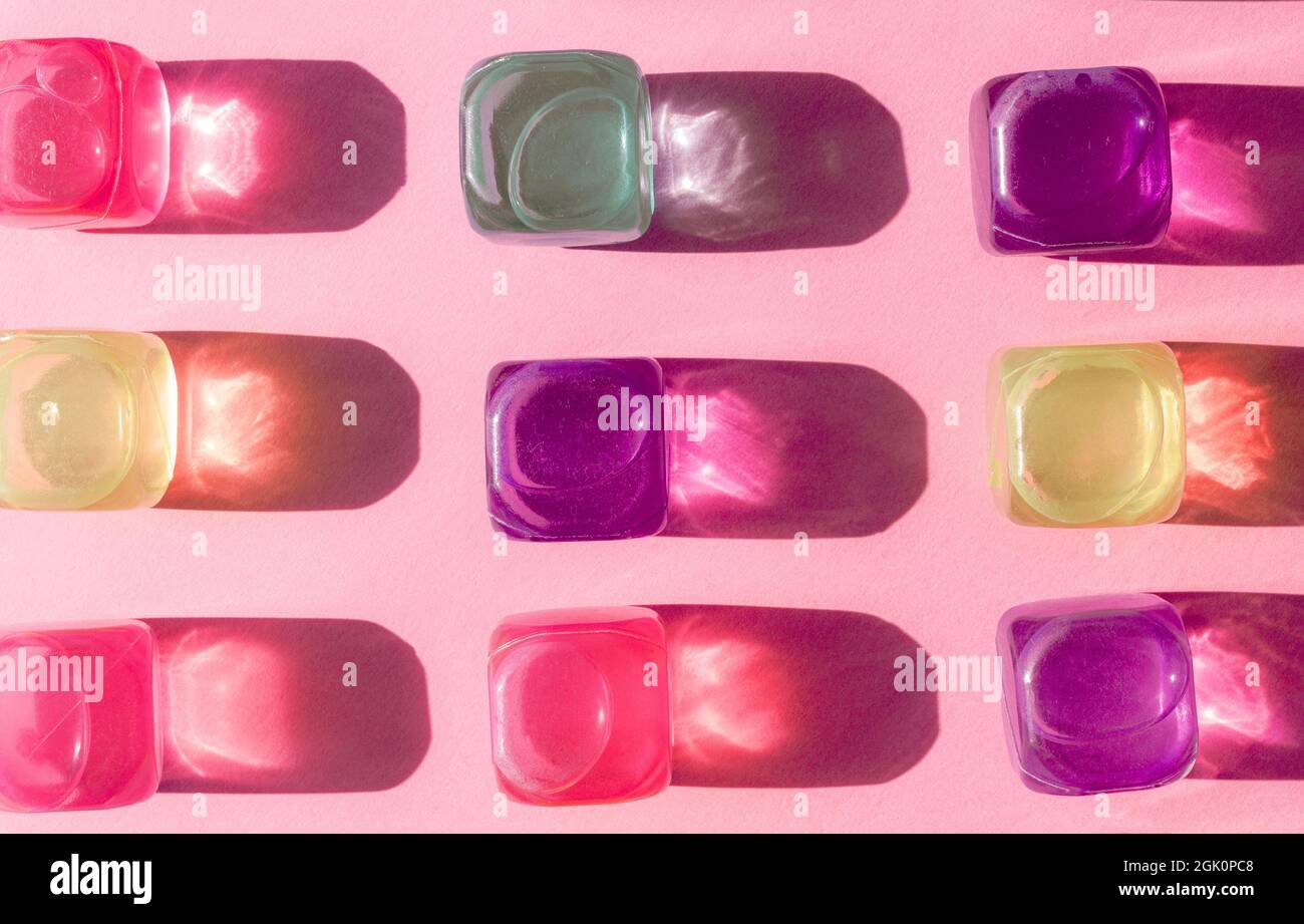 Kreatives Layout mit bunten Plastikwürfeln aus Eis in der Mittagssonne und harten Schatten im Hintergrund. Sommermockup. Flach liegend. Stockfoto