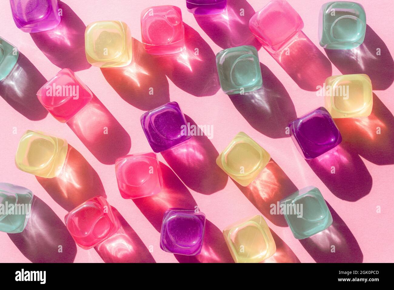 Kreatives Layout mit bunten Plastikwürfeln aus Eis in der Mittagssonne und harten Schatten im Hintergrund. Sommermockup. Flach liegend. Stockfoto
