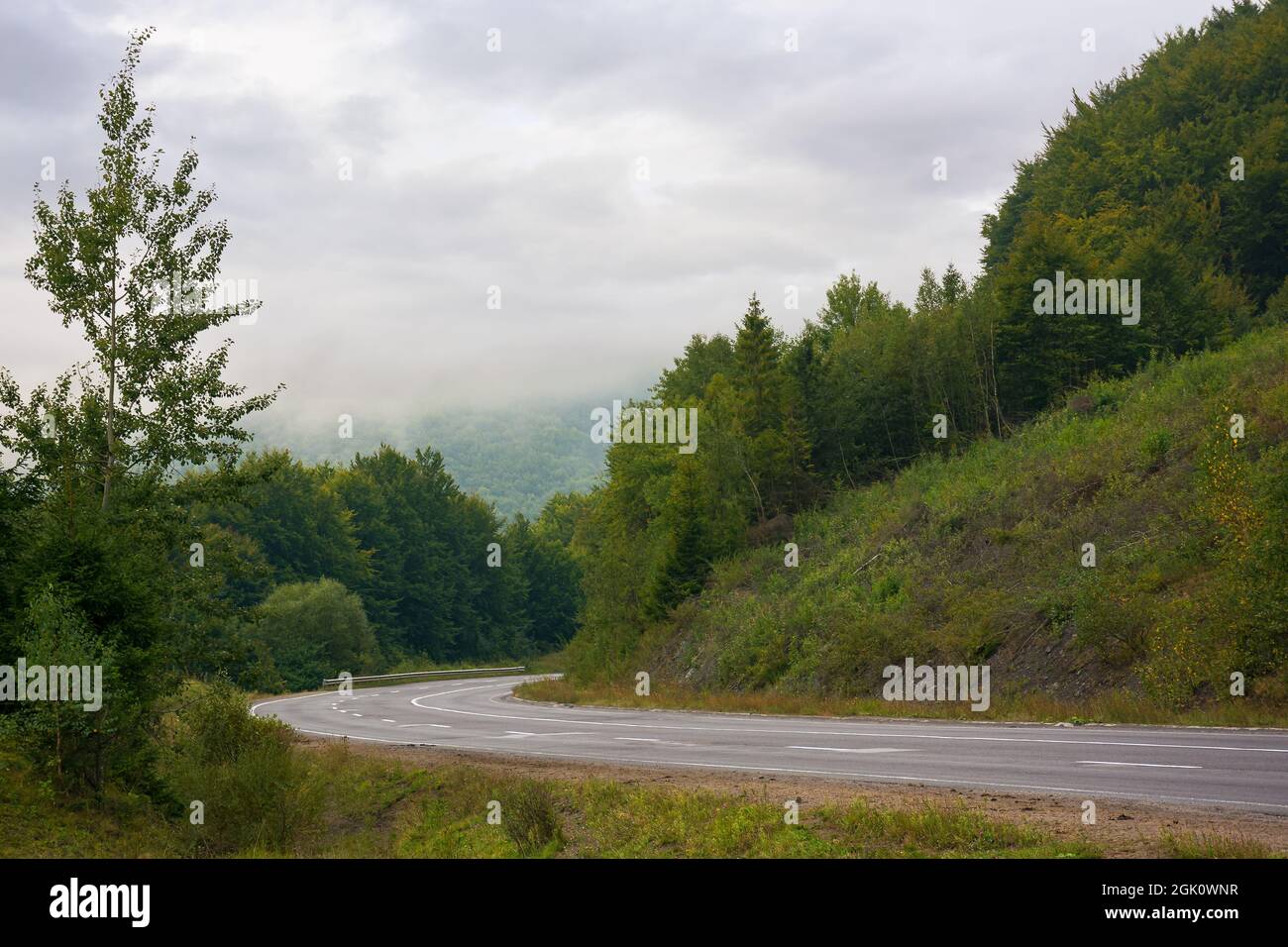 Asphaltierte Straße durch Berge an einem bewölkten Tag. Wunderschöne ländliche Landschaft im Frühherbst Stockfoto