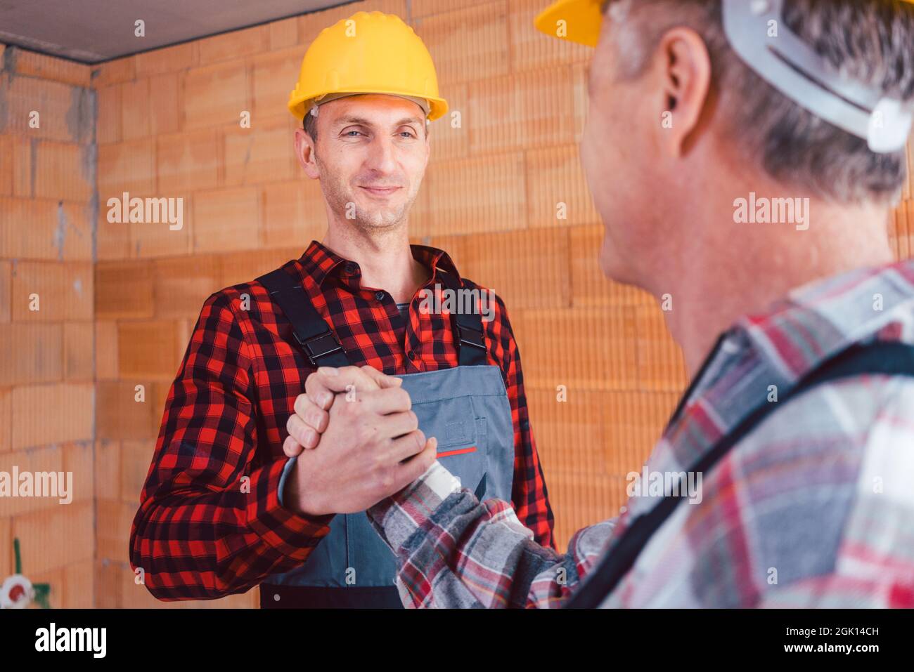 Männlicher Bauingenieur und Baumeister, der die Hände schüttelt Stockfoto