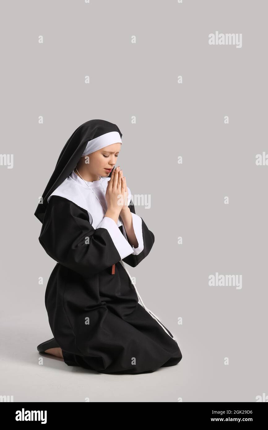 Junge betende Nonne auf grauem Hintergrund Stockfoto