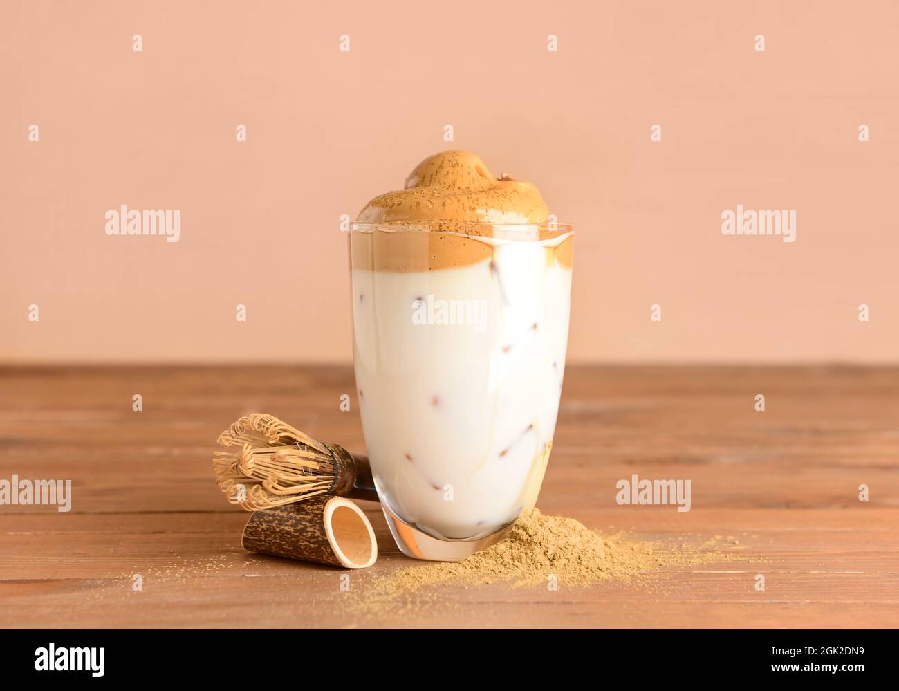 Ein Glas schmackhafter dalgona hojicha, Chasen und Pulver auf dem Tisch Stockfoto