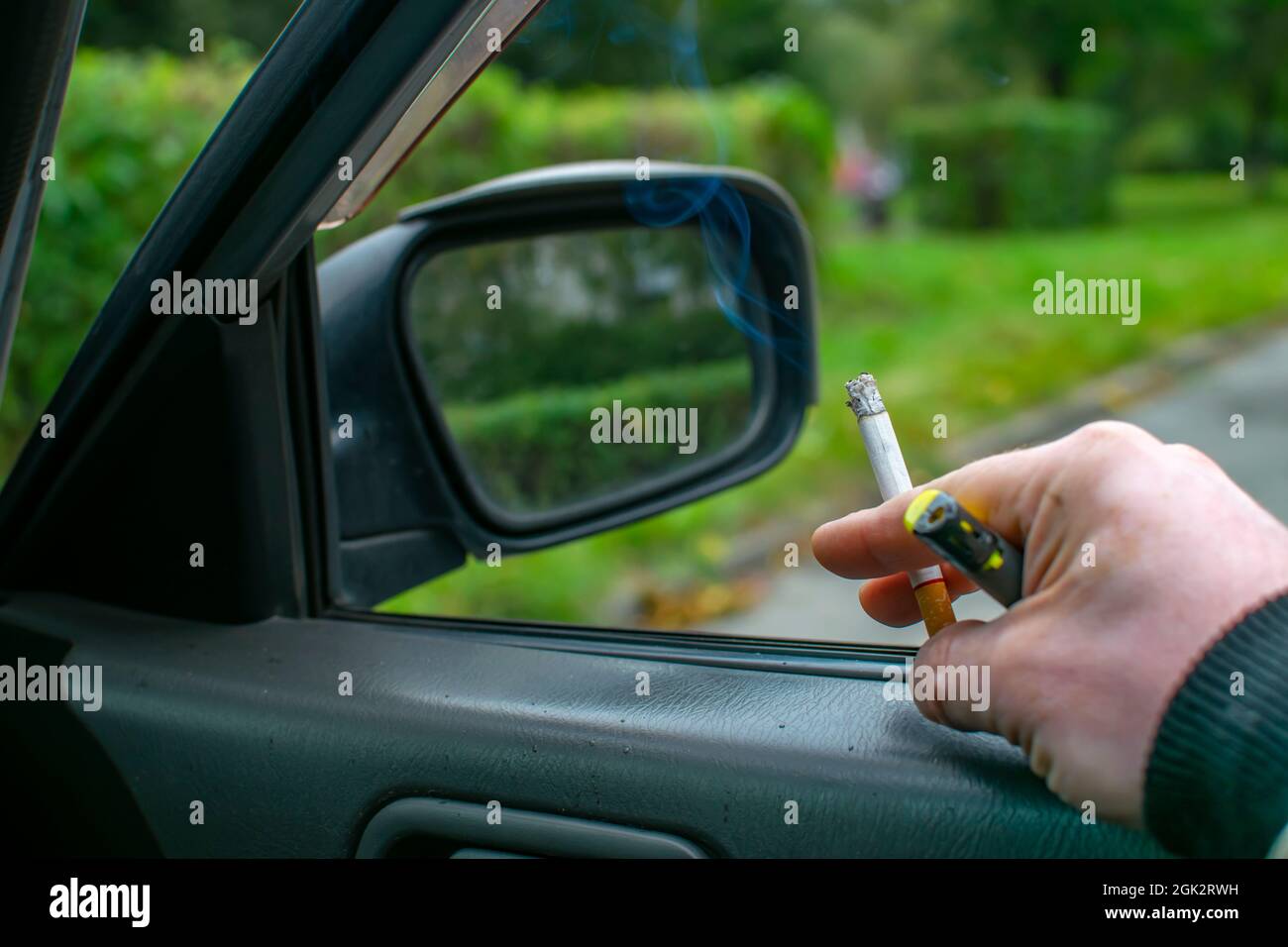 Eine rauchende Zigarette mit einem Filter in der Hand des Fahrers Stockfoto