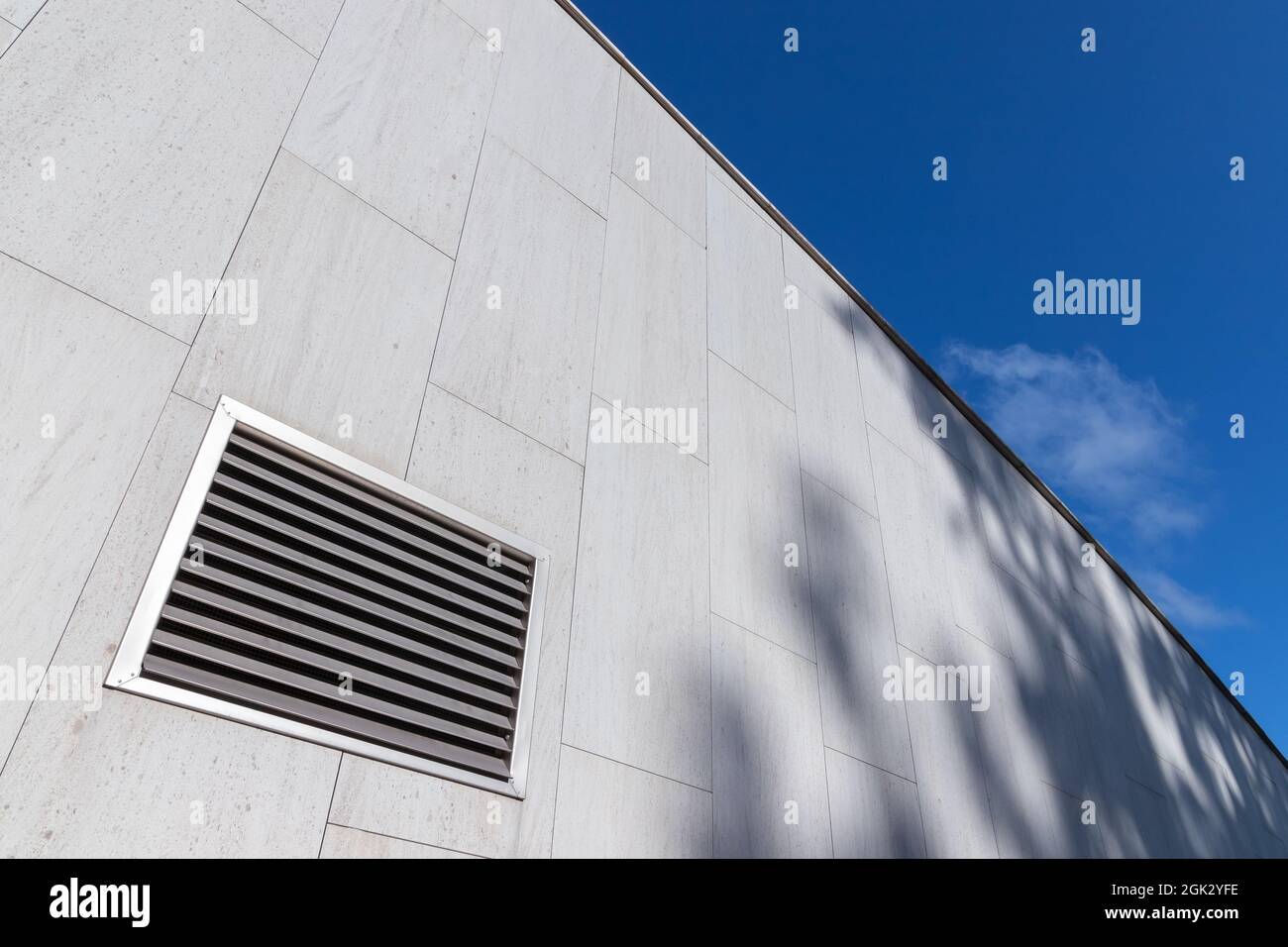 Fragment der abstrakten Industriearchitektur, graue Steinmauer mit quadratischem Lüftungsgitter Stockfoto