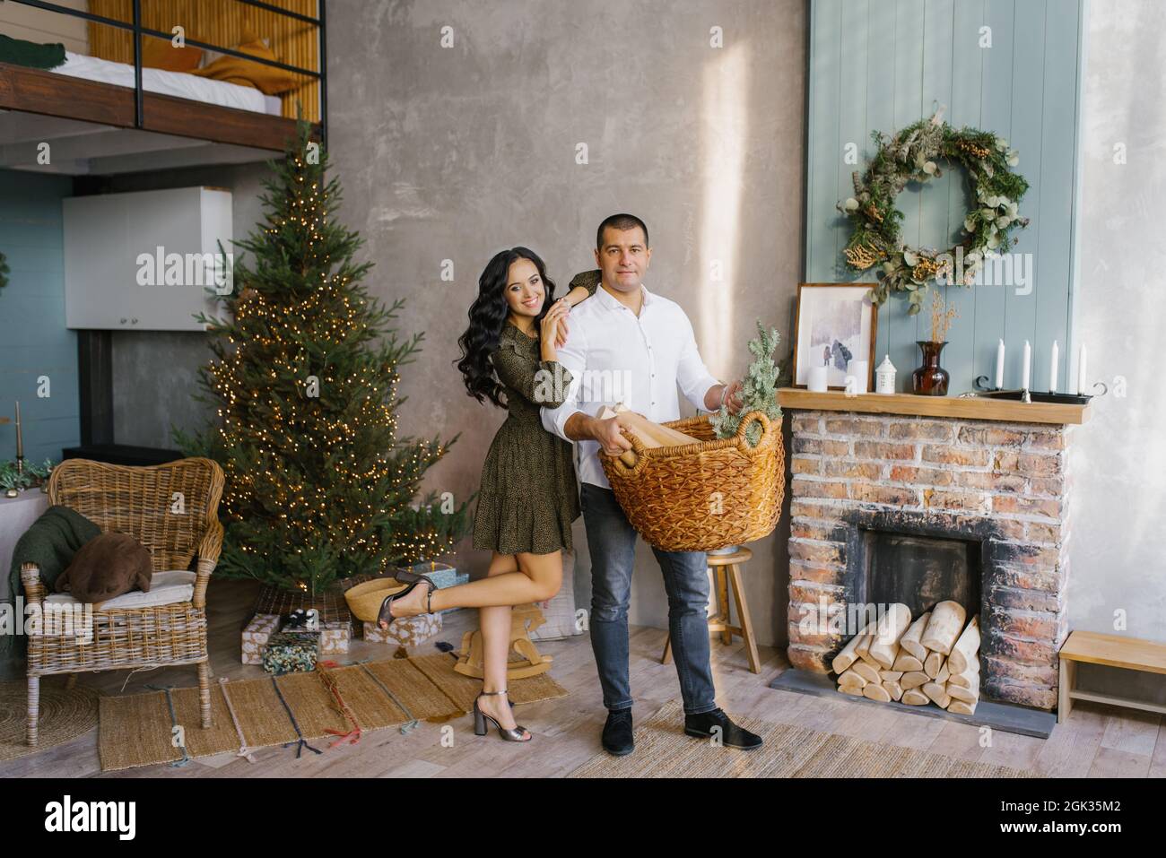 Ein verliebtes Paar freut sich, Neujahr und Weihnachten gemeinsam im Wohnzimmer eines Landhauses im skandinavischen Stil in der Nähe der Tanne zu feiern Stockfoto