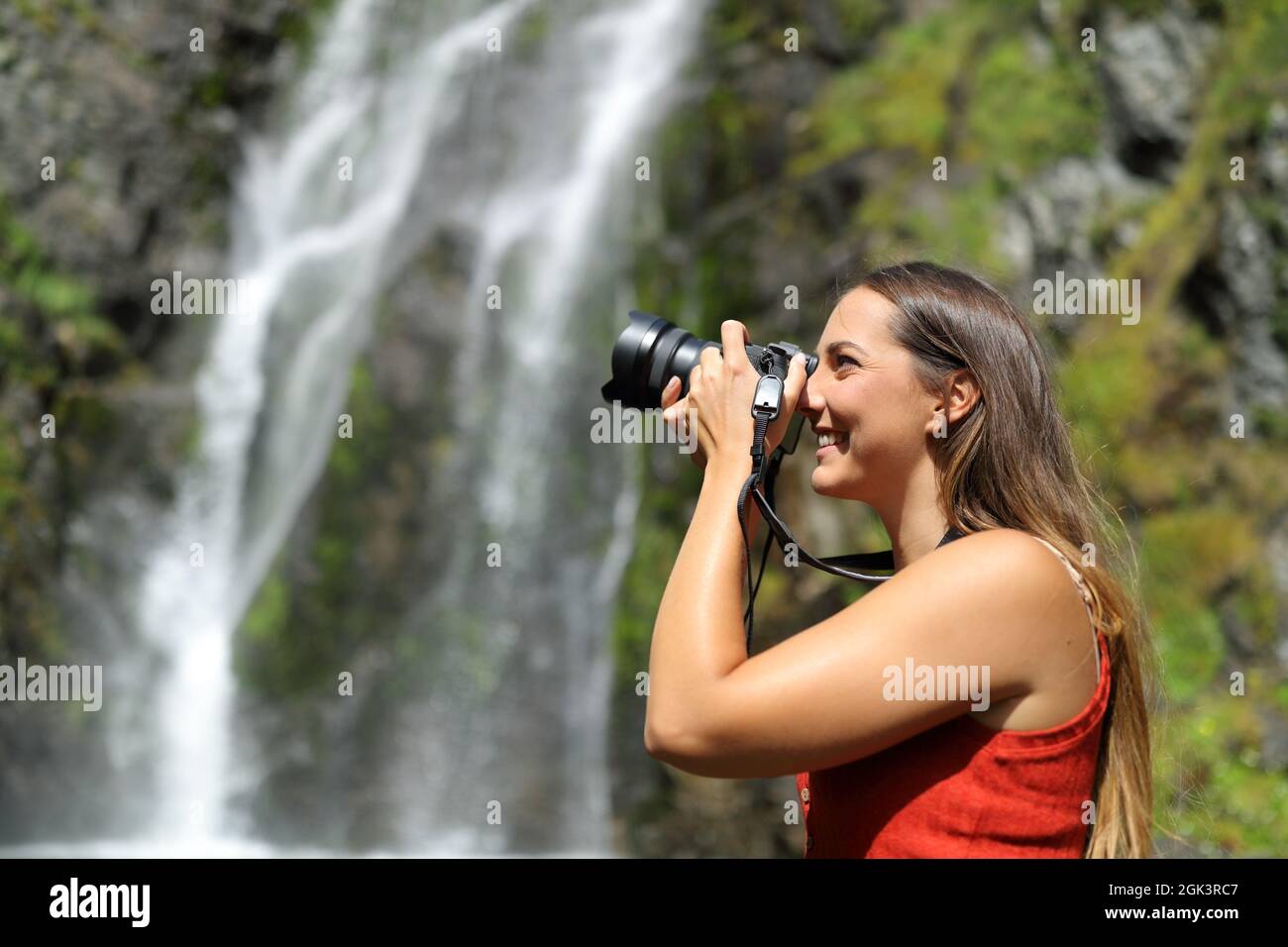 Seitenansicht Porträt einer glücklichen Frau, die Fotos mit spiegelloser Kamera in der Natur macht Stockfoto