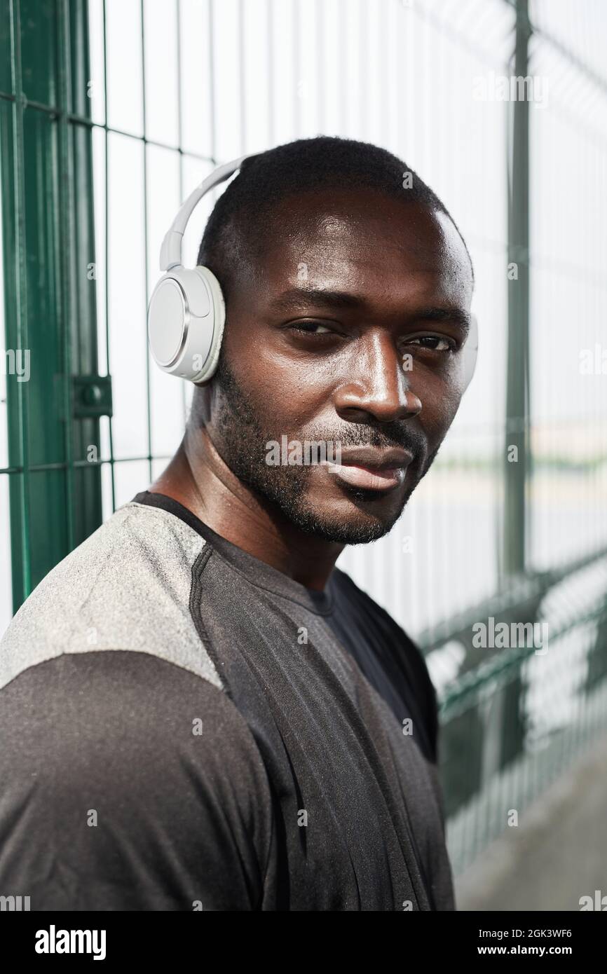 Porträt eines jungen afrikanischen Athleten in kabellosen Kopfhörern, der die Kamera im Freien betrachtet Stockfoto