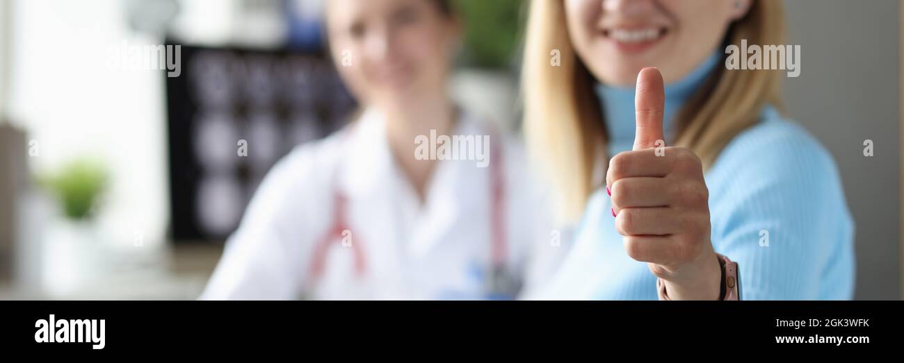 Eine Patientin zeigt beim Arzttermin eine Geste mit dem Daumen nach oben Stockfoto