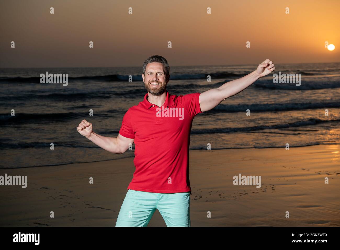 Glücklicher Mann feiert Erfolg über dem Meer auf Sonnenuntergang Sommerstrand, Glück Stockfoto
