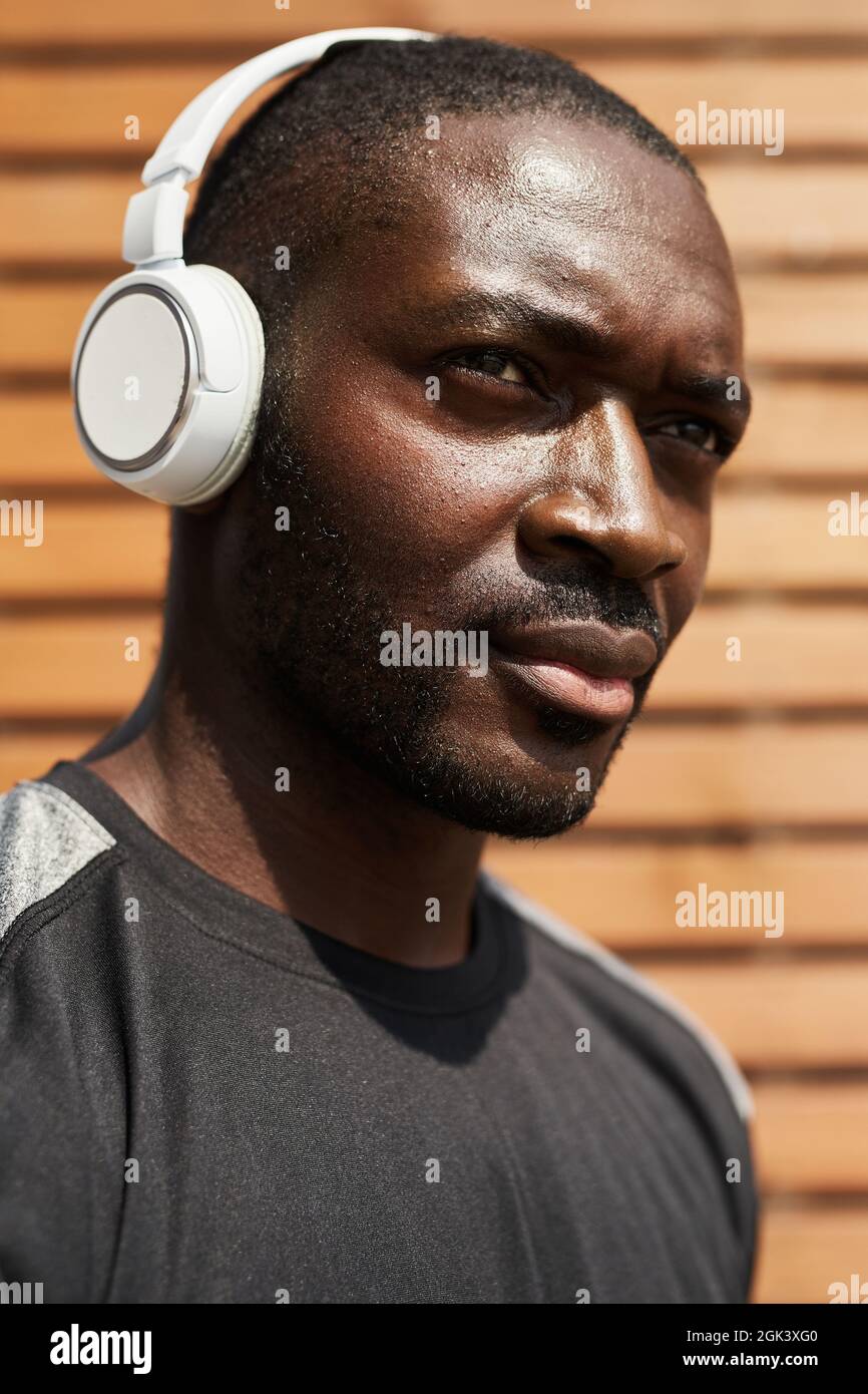 Nahaufnahme eines nachdenklichen afrikanischen Mannes, der im Freien Musik in Kopfhörern hört Stockfoto