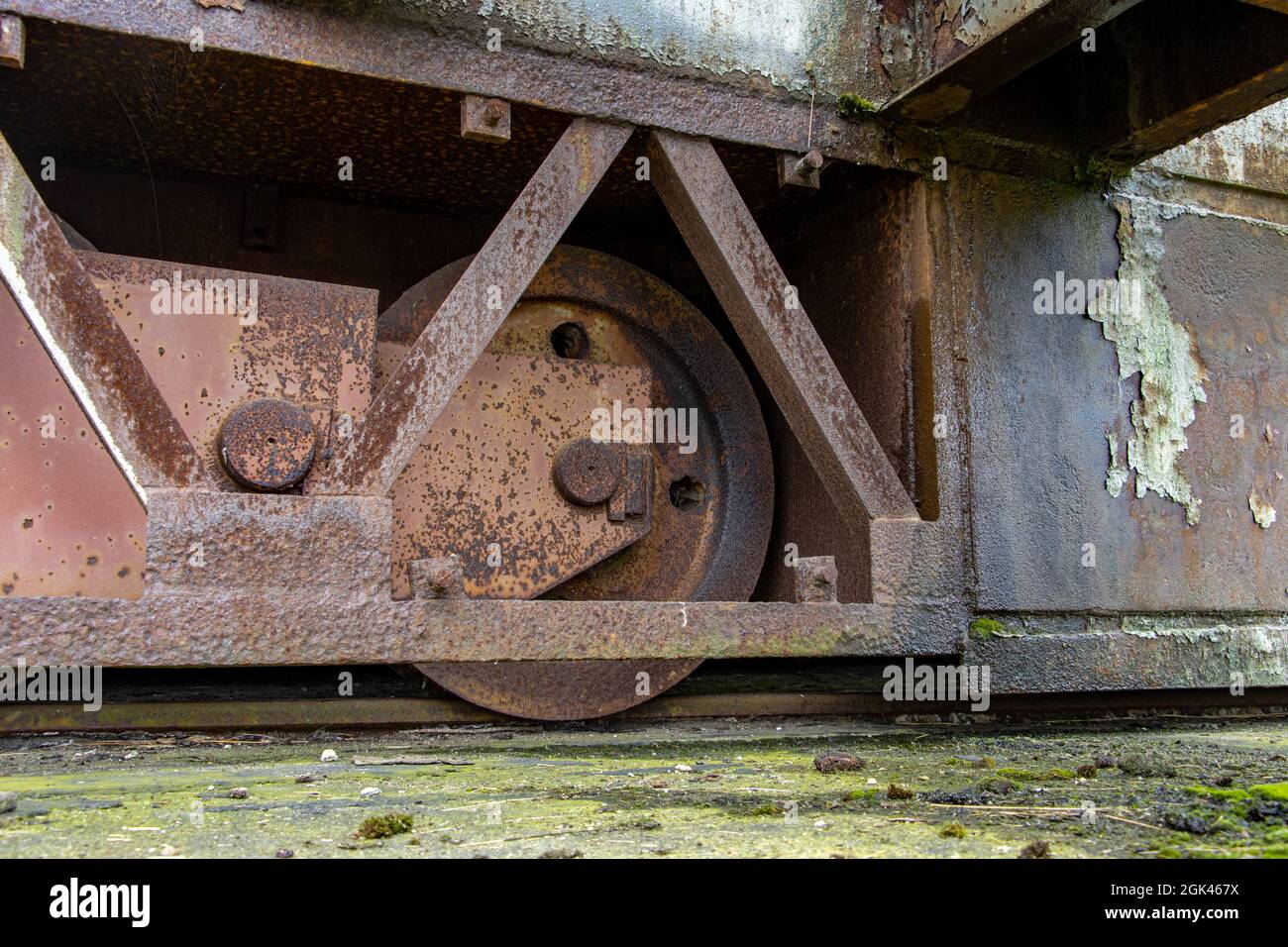 Ein rostig eisernes Rad auf der Schiebetürstange. Detail des Rades eines Stahlbetontors auf einer Schiene. Stockfoto