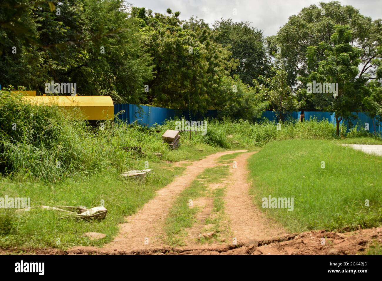 Schmutzige nasse Straße Pathway und grüne Bäume in Regenzeit Hintergrund Stockfoto