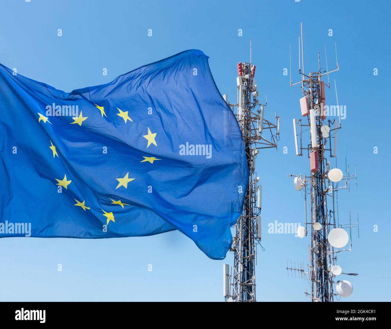 Mobilfunkantenne, Antennen und EU-Flagge am blauen Himmel. Roaming-Gebühren, Spyware... Europa-Konzept. Stockfoto