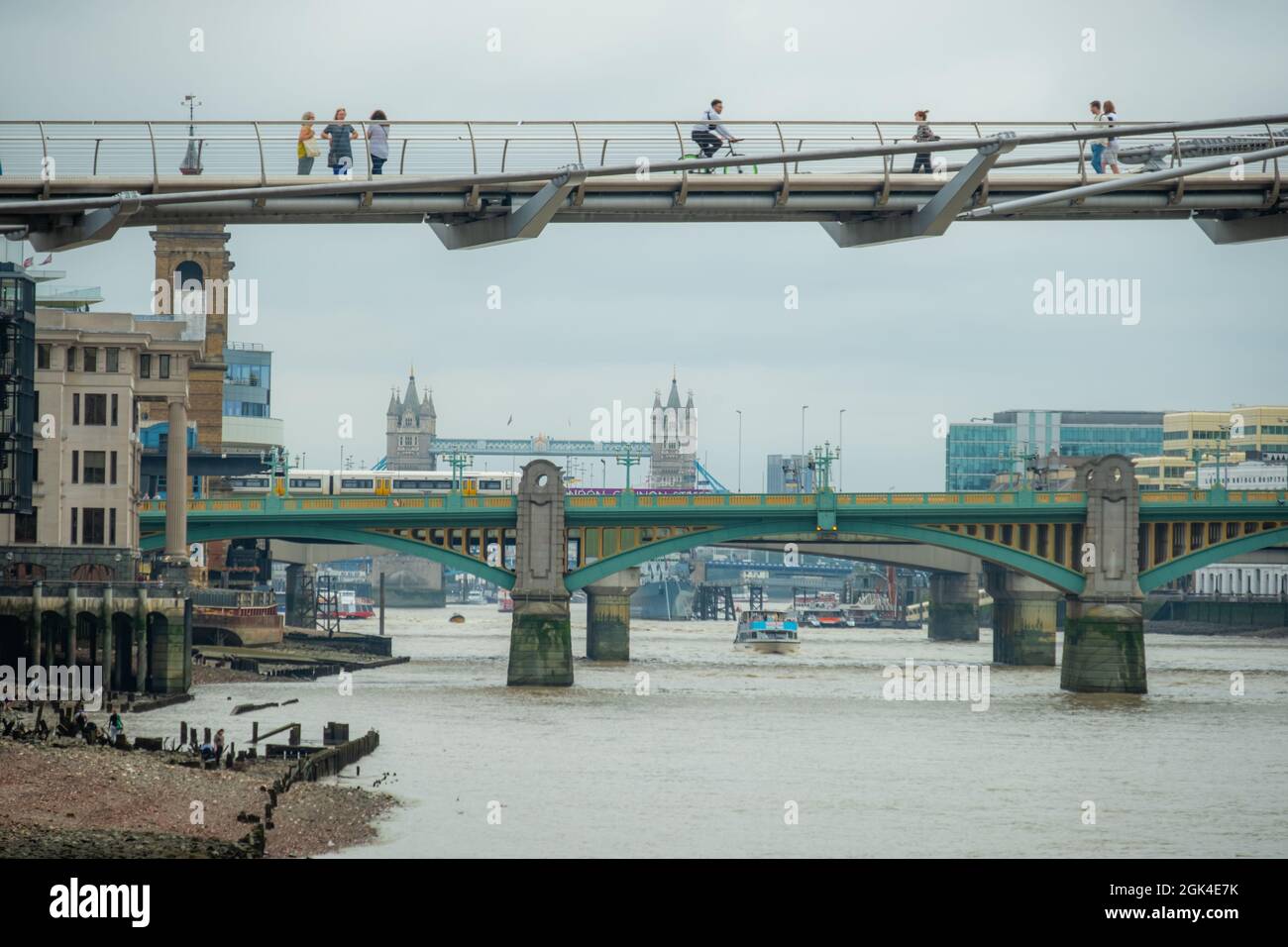 London, September 2021: Zwei Menschen blicken von der Millennium Bridge über die Themse auf die Londoner Brücken Stockfoto