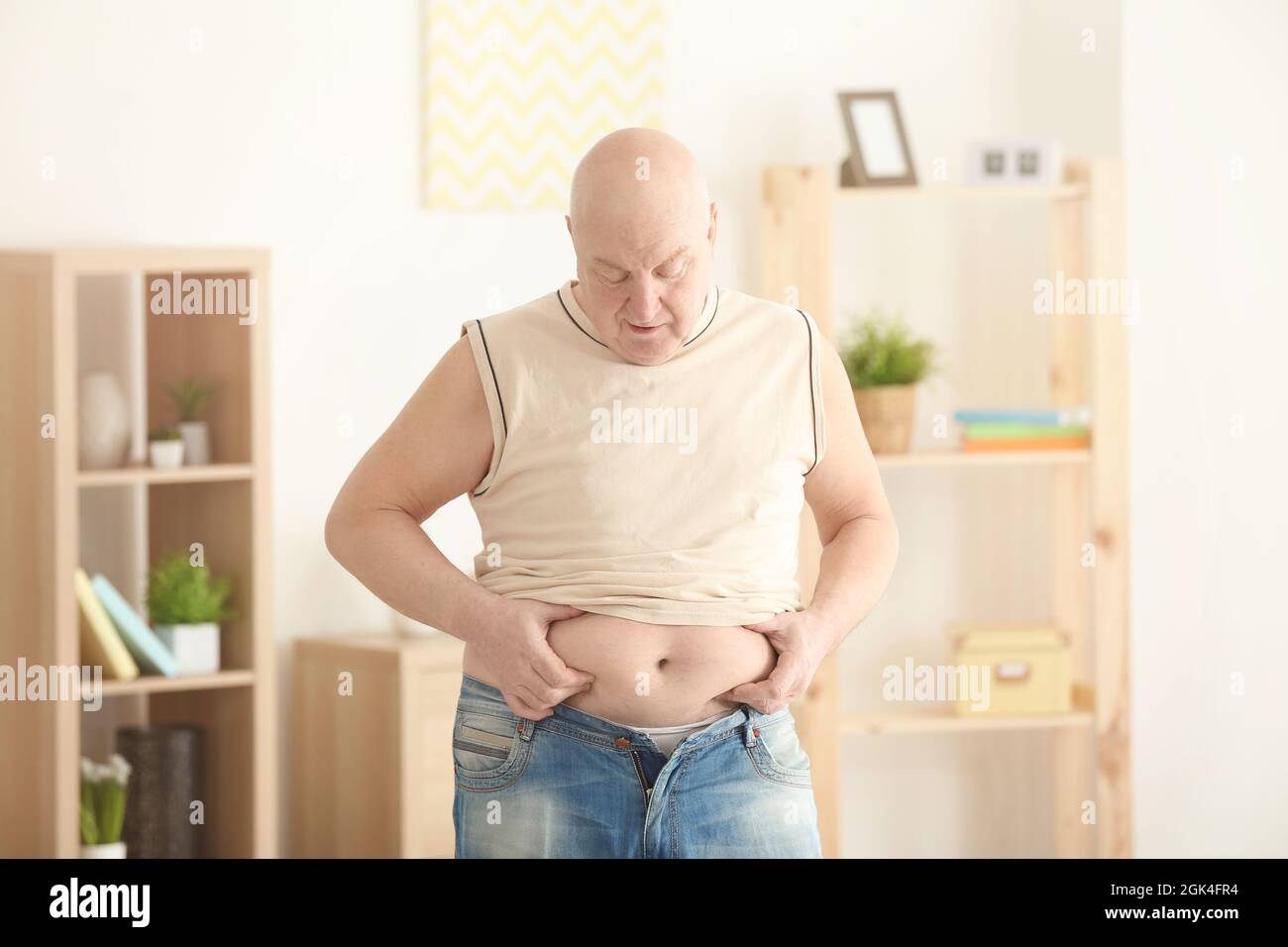 Fat Senior Mann versucht, auf enge Kleidung zu Hause setzen.  Gewichtsverlust Konzept Stockfotografie - Alamy